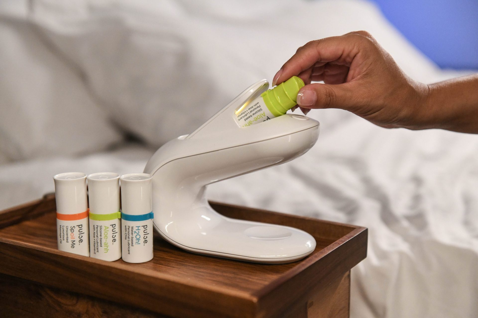 A pod for silicone-based sexual lubricant is inserted into the Pulse Warmer heating system on a bedside table.