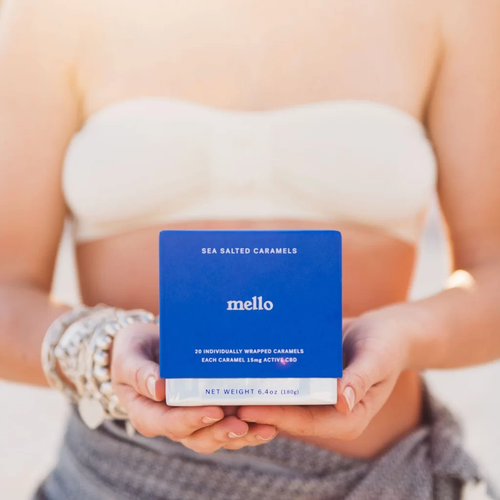 Model holds packaging for Mello Sea Salted CBD Caramels from sexual wellness company. Mello Daily